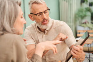 Woman looking at the tablet screen while her husband telling something to her